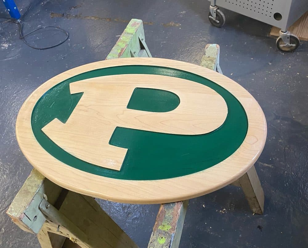 Carved Green Bay Packers logo on a round wood plaque