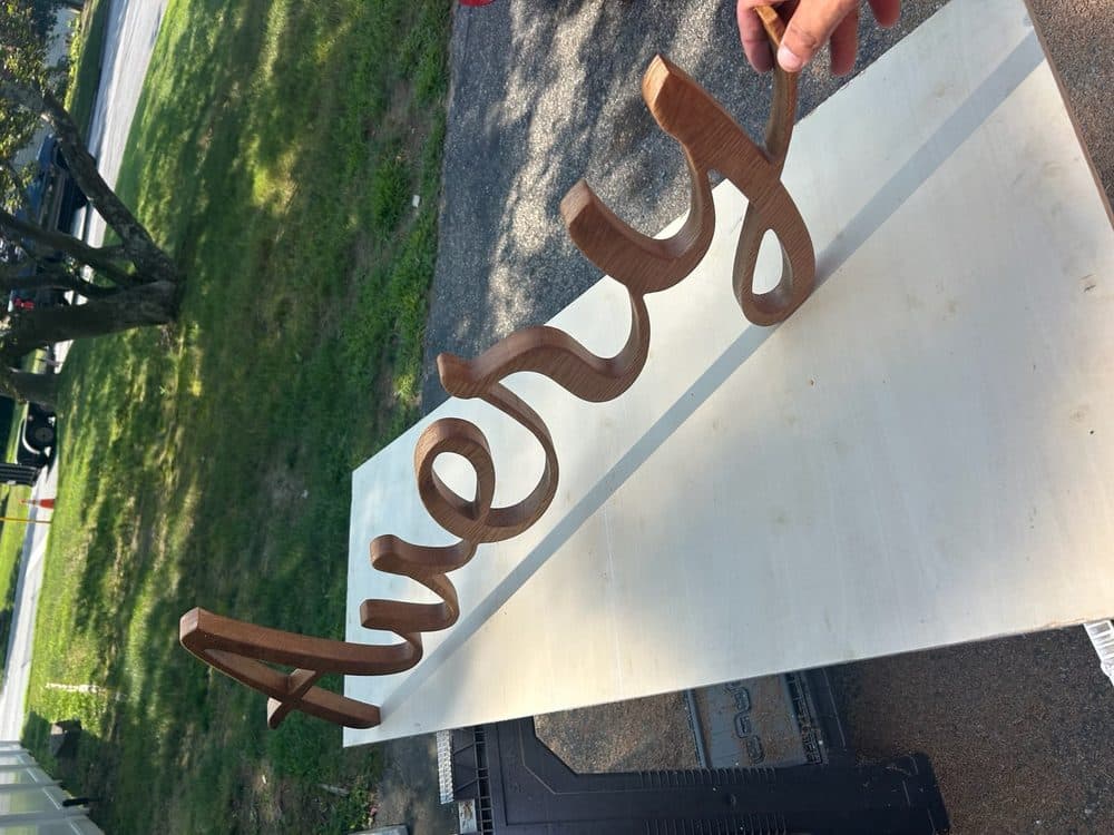 Custom scroll-cut oak name sign in flowing cursive script