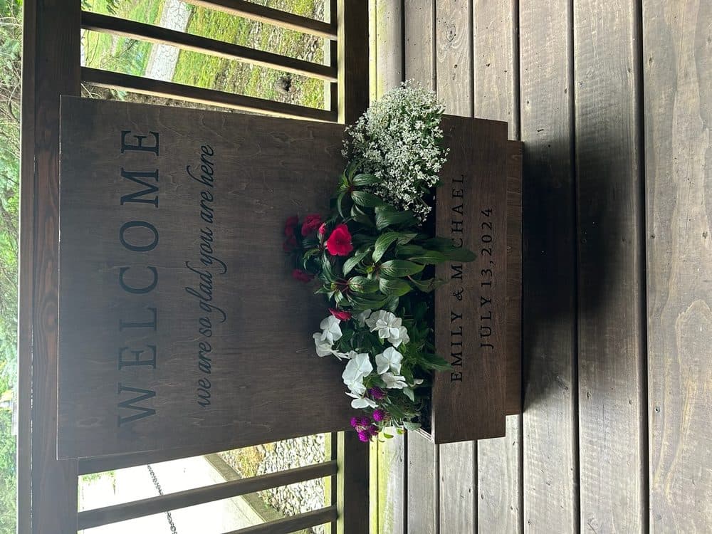 Custom wood wedding welcome sign displayed with floral planter