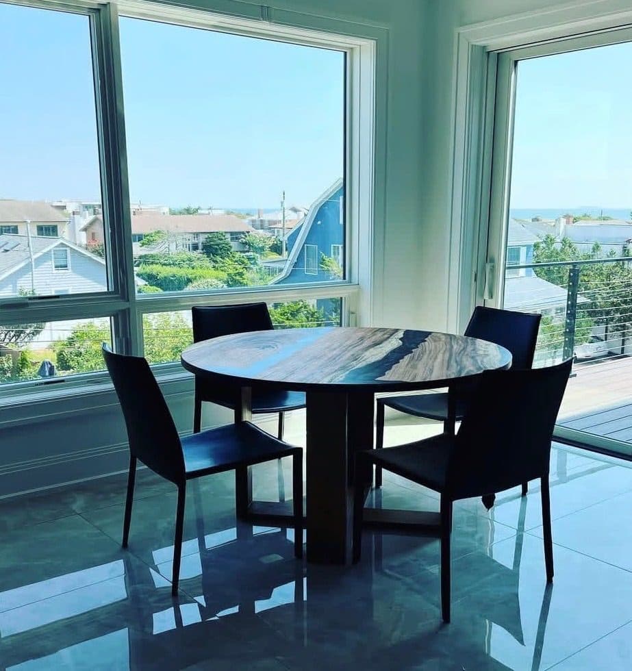 Round epoxy resin dining table with grey wood and blue resin in coastal home with ocean views