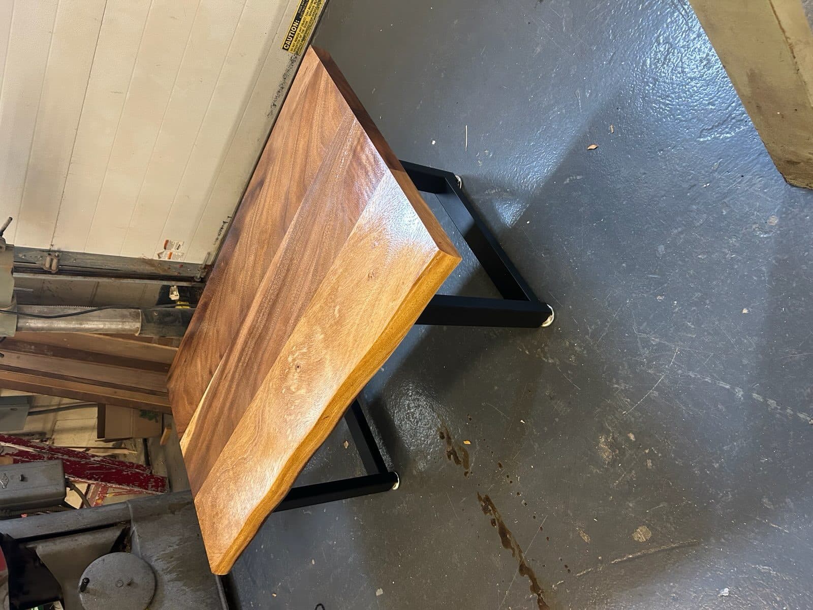 Walnut slab desk with black metal trapezoid legs in a home office